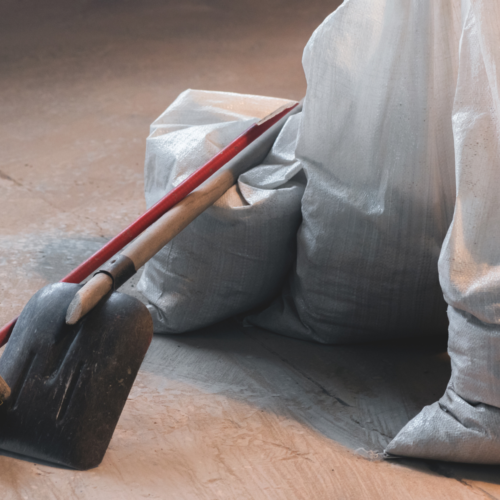 Shovel and bags of construction debris in a clean, unfinished space, representing post-construction cleaning services by Clean Corps.