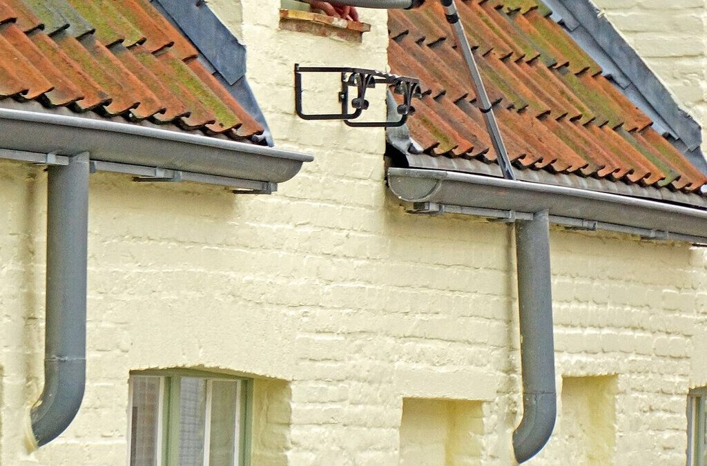 Roof gutters and downspouts along a roofline needing maintenance