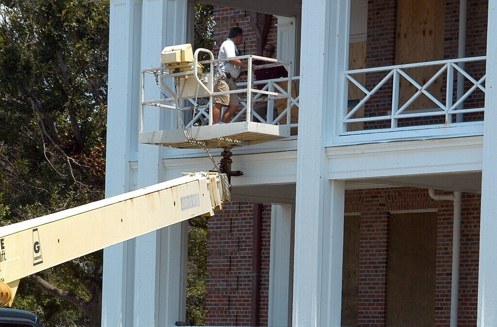 Worker installing hurricane window protection ahead of storm season on a Florida property