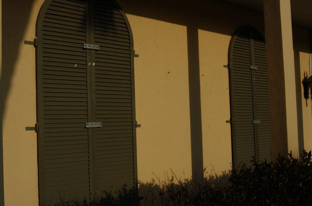 Wood hurricane shutters installed on a house ahead of storm season, representing removable storm panel prep for an Orlando vacation rental