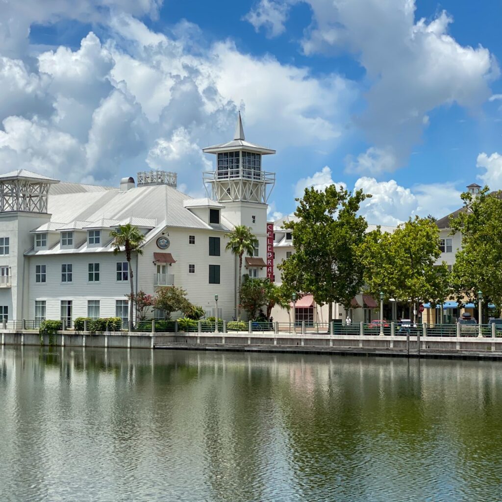 Lakefront hotel with a lookout tower and tree-lined waterfront promenade in downtown Celebration, Florida