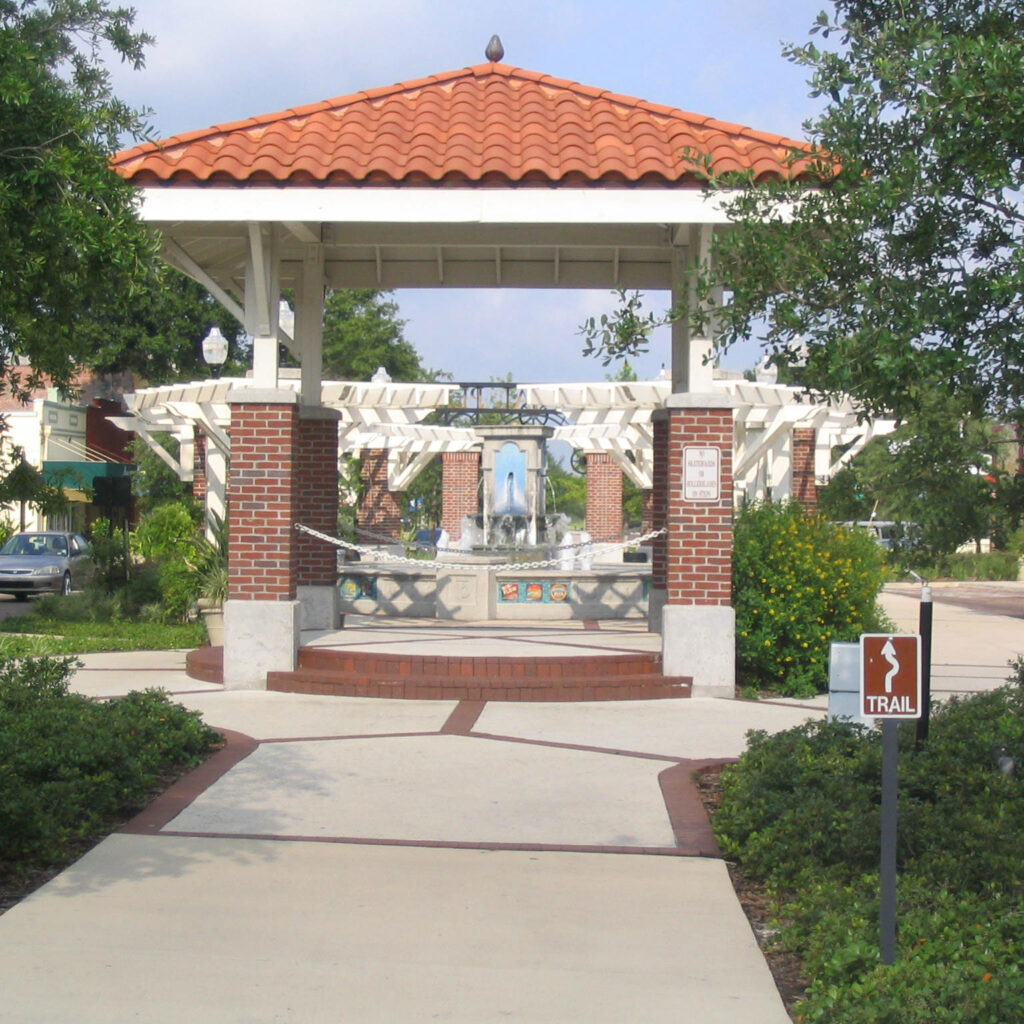 Tile-roofed brick gazebo and fountain on the West Orange Trail in downtown Winter Garden, Florida, framed by oak trees